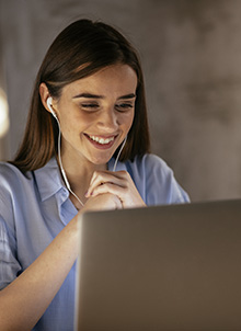 Young professional woman smiling at a computer screen.
